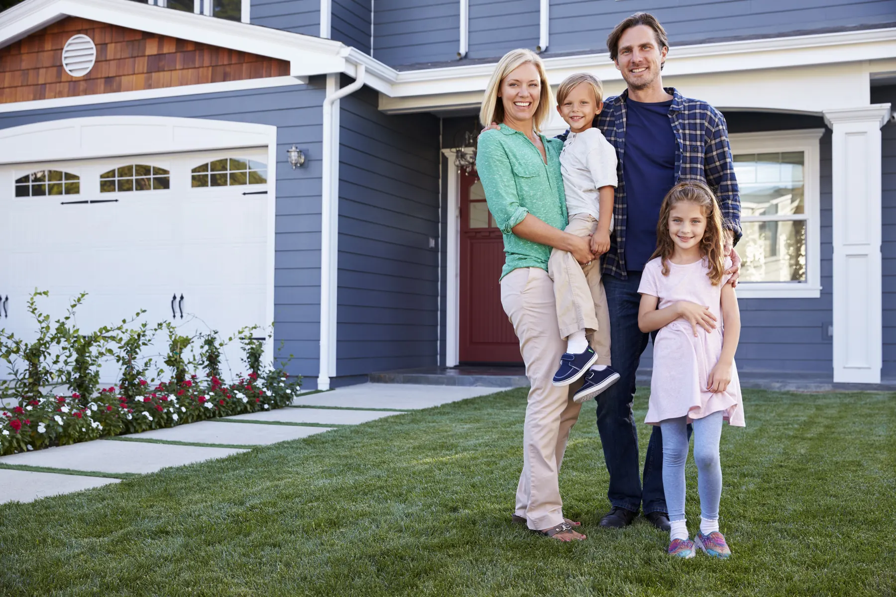 Smiling family standing on the front lawn of their two-story home